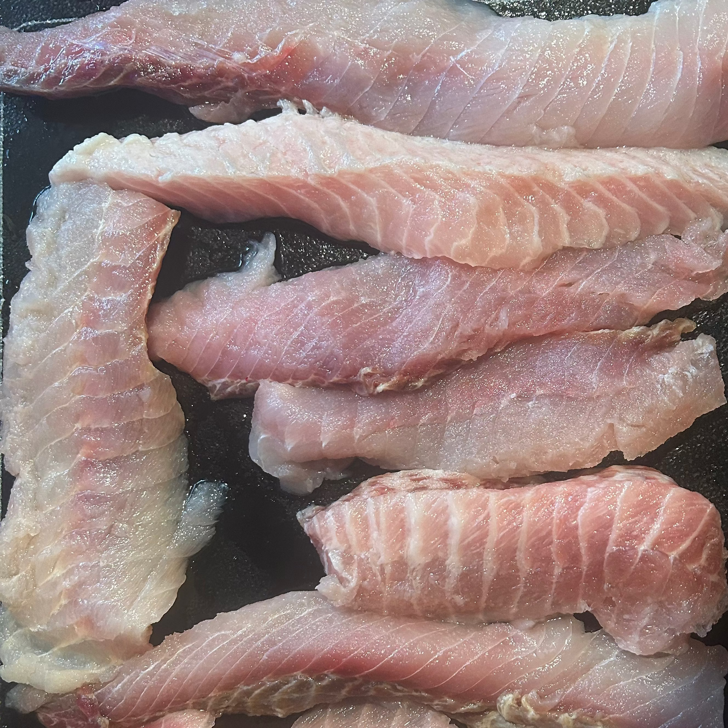 Raw fish fillets on a dark surface