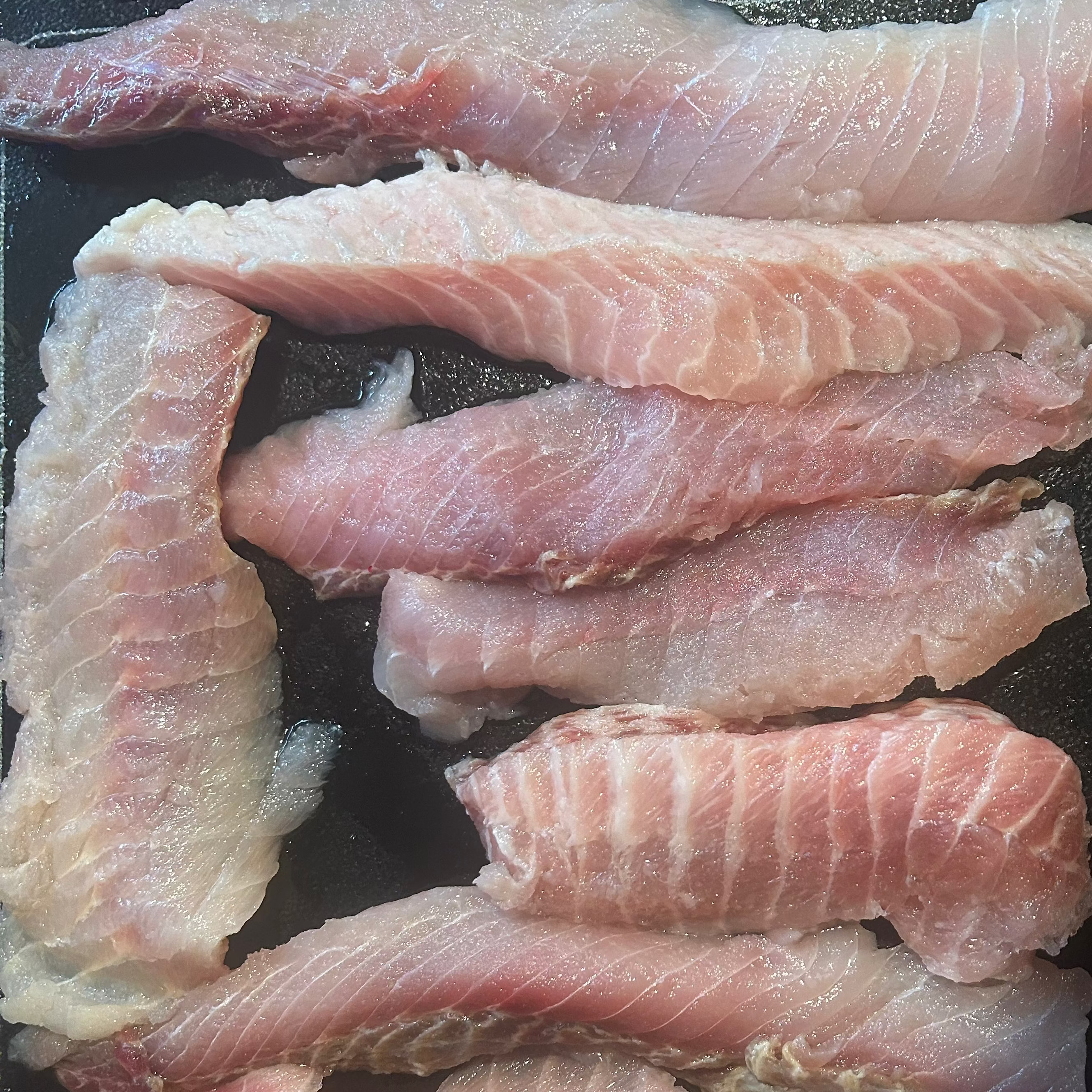 Raw fish fillets on a dark surface